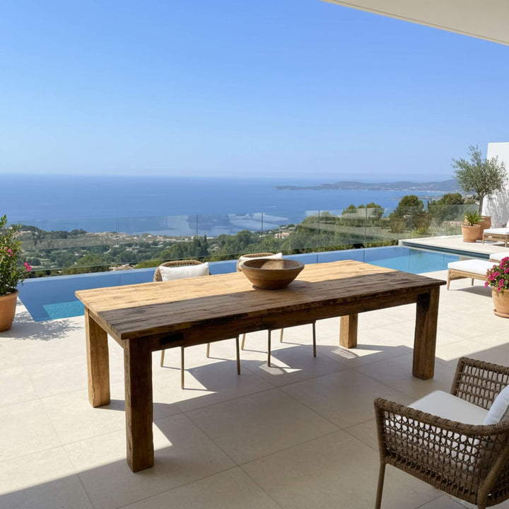 Sleeper rail train dining table with chairs on a patio overlooking a scenic view of the ocean.