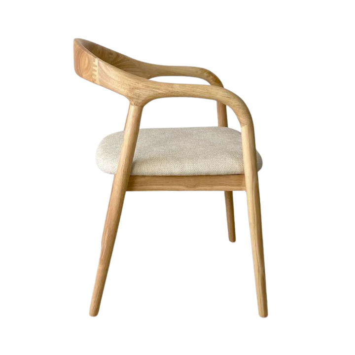 Side view of the Sora dining chair showing its sculptural silhouette and slender wooden legs.