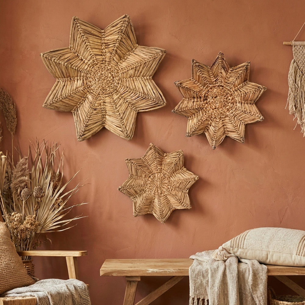 Woven Star wall deco plate art pieces on a terracotta wall with a wooden bench and plants.