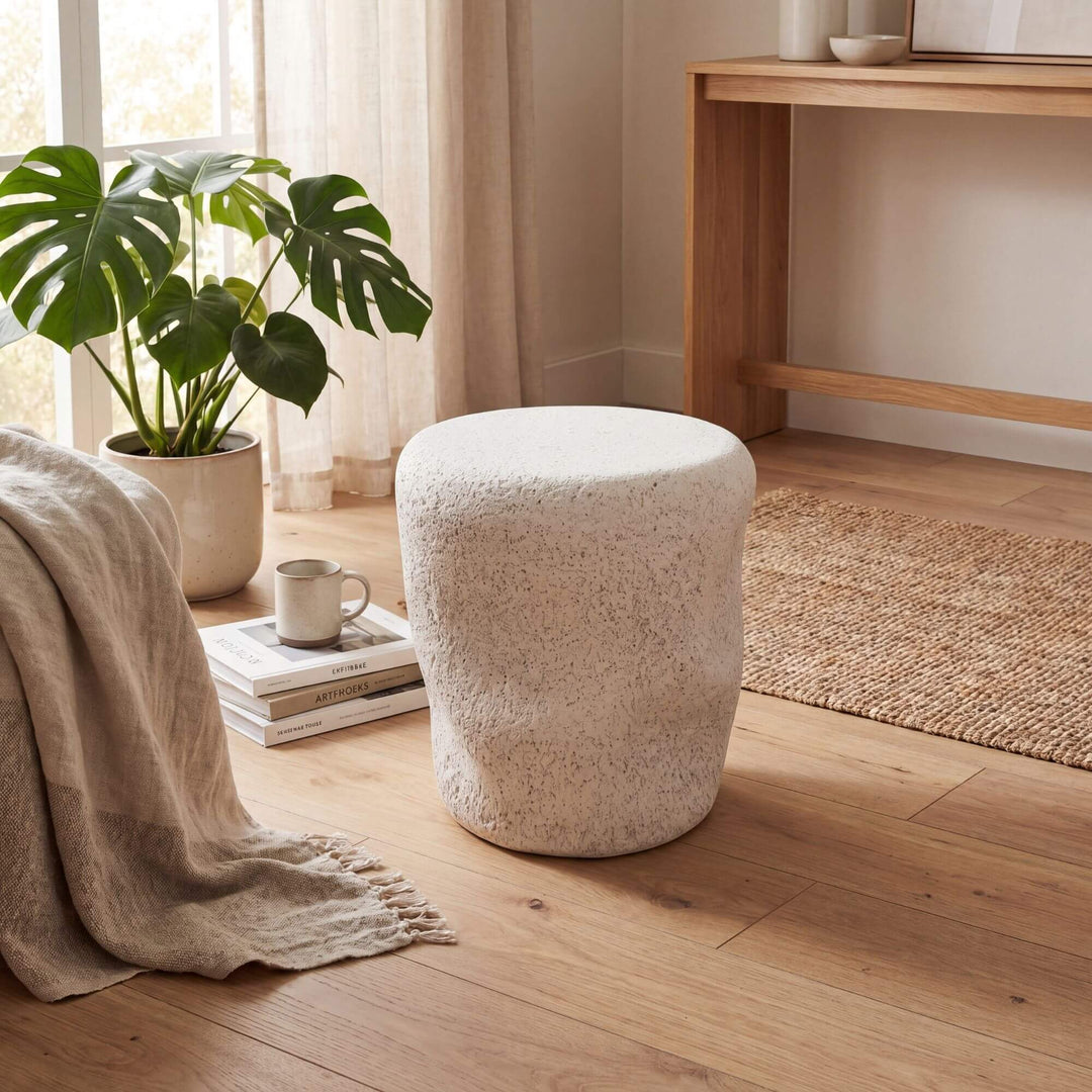 Styled interior setting featuring the stone look stool beside an armchair in a warm natural living space.
