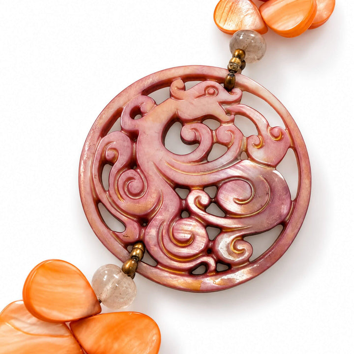 Close-up of the carved pink mother-of-pearl medallion on the Sunset Nacre Necklace