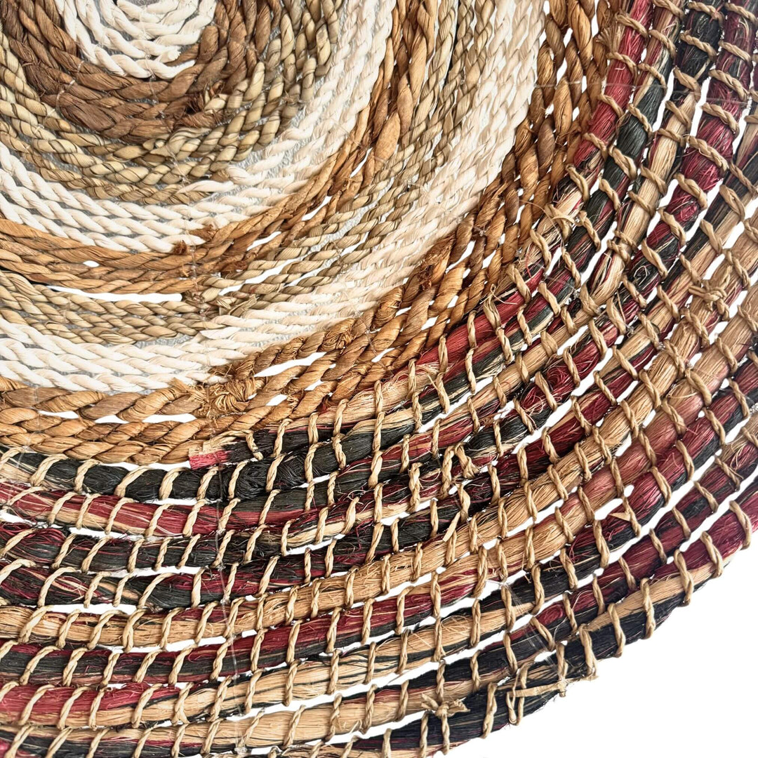 Close up of Samara Wall Deco Plate, handwoven from abaca, cotton, and rattan with concentric natural and earthy-toned patterns.

