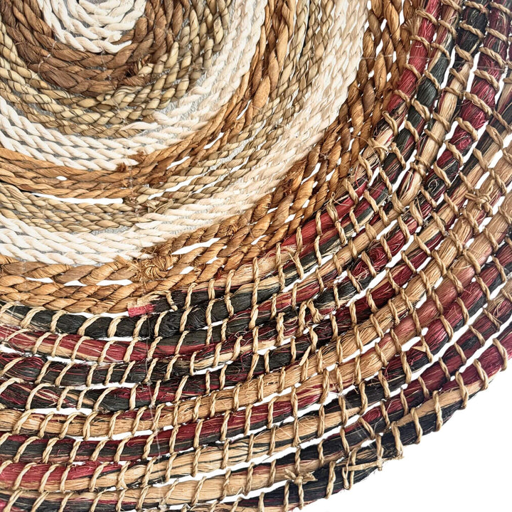 Close up of Samara Wall Deco Plate, handwoven from abaca, cotton, and rattan with concentric natural and earthy-toned patterns.

