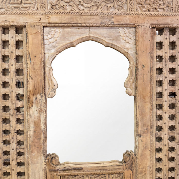 Close-up of the central arched mirror section showing the ornate carved frame and aged finish.