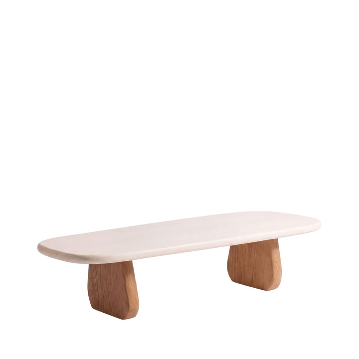 Front angled view of the Tao coffee table with an elongated off-white microcement top and sculptural sungkai wood legs