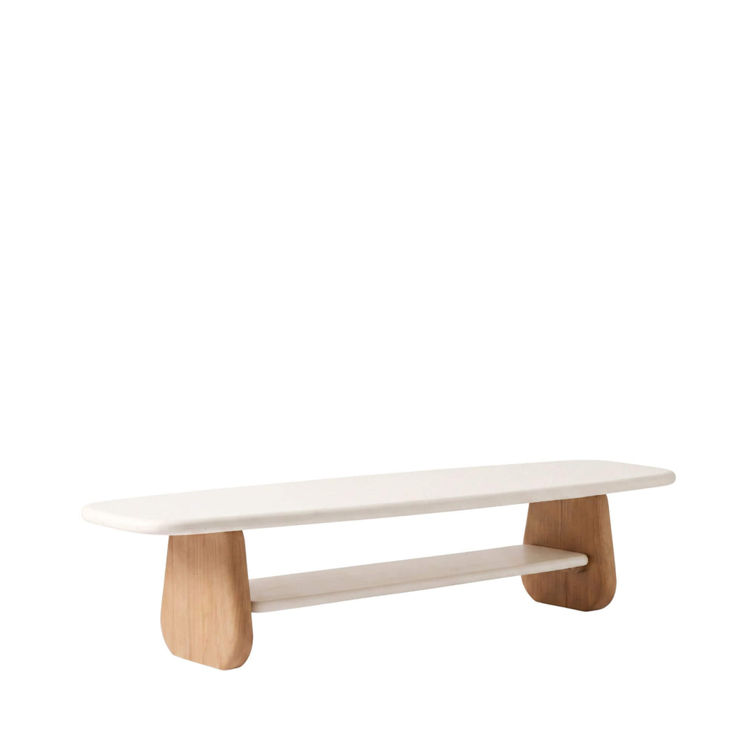 Front angled view of the Tao TV console with an elongated off-white microcement top, lower shelf, and sculptural sungkai wood supports