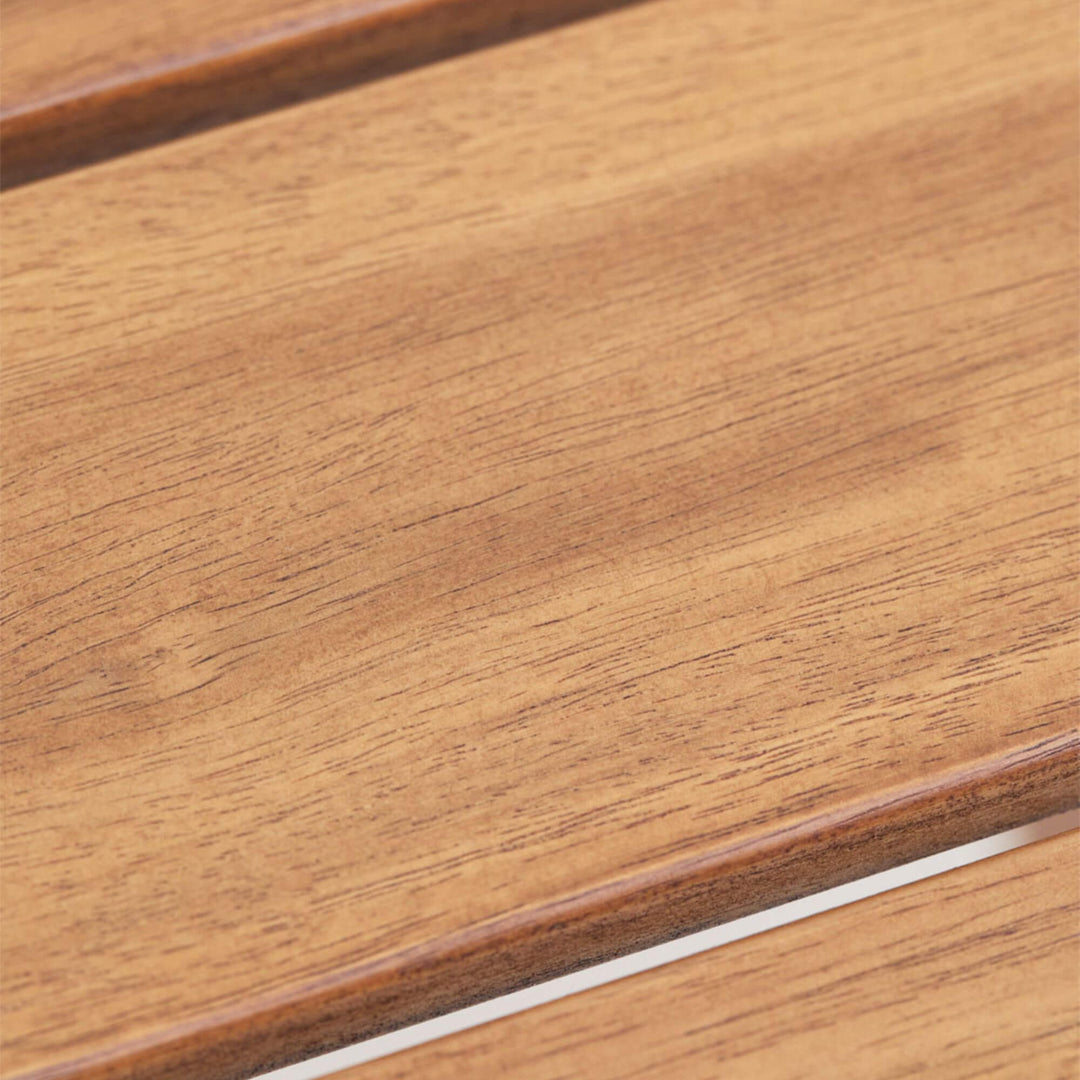 Detail view of the Tavira bar table showing the warm acacia wood grain and smooth slatted tabletop finish