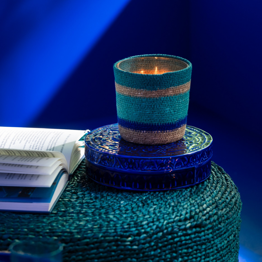 Tazirit candle lit on a table creating a warm coastal ambiance.