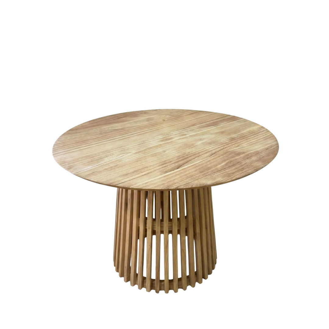 Front view of the Thai dining table showing its round sungkai wood top and sculptural slatted pedestal base.
