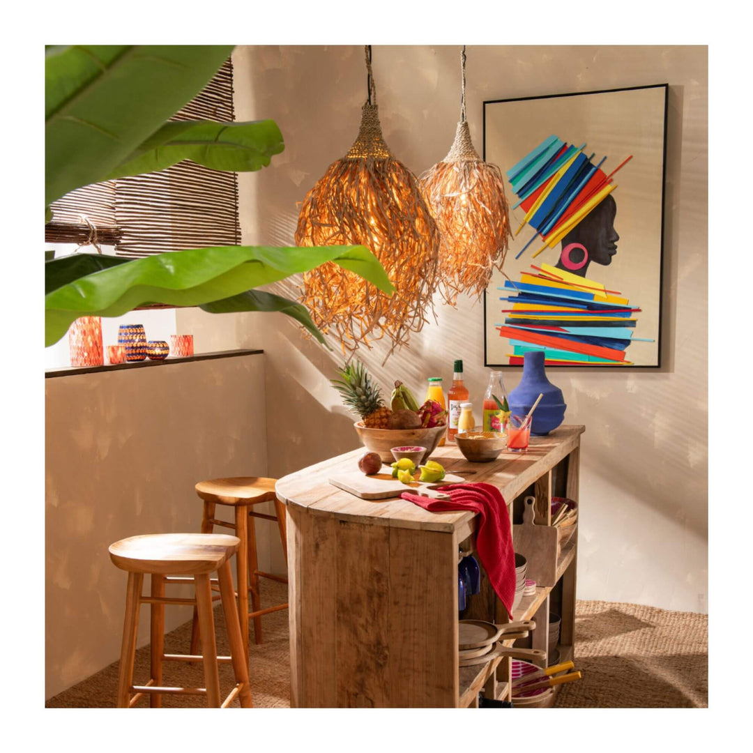 Interior setting with Tomasa Summer Painting hanging above a rustic wooden table, styled with tropical lighting and natural decor.