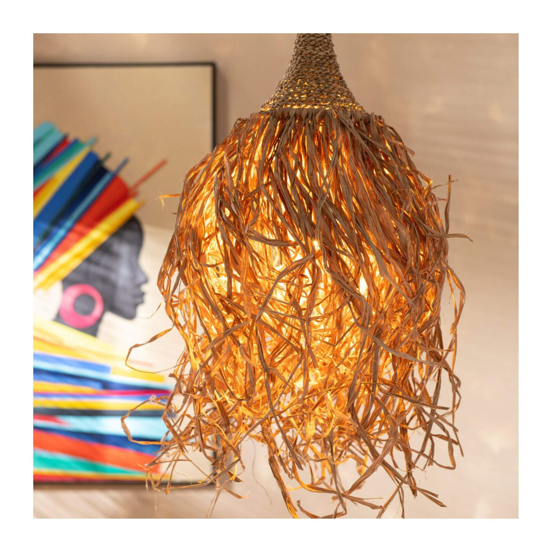 Boho-style lamp made of natural fibers glowing warmly with the colorful Tomasa Summer Painting visible in the background.