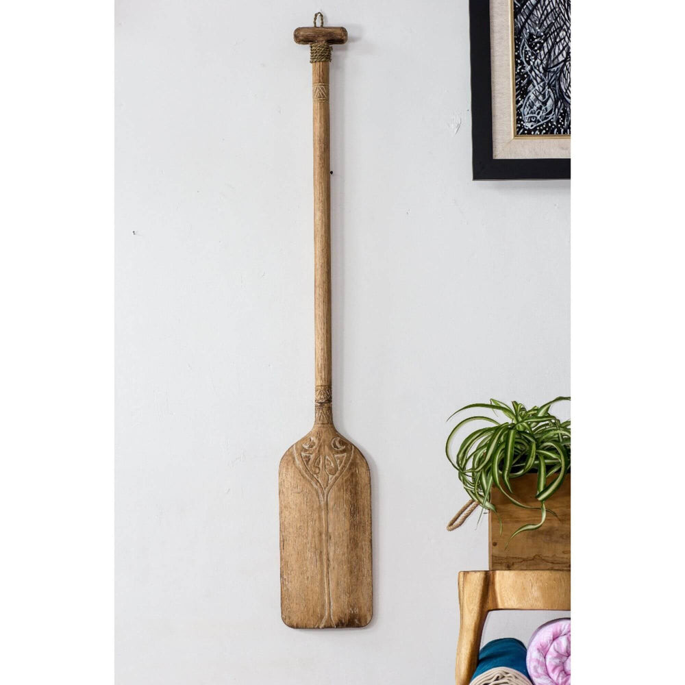 Natural wood paddle wall decor hanging in a bright room.