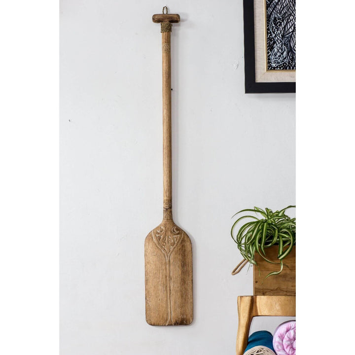 Natural wood paddle wall decor hanging in a bright room.