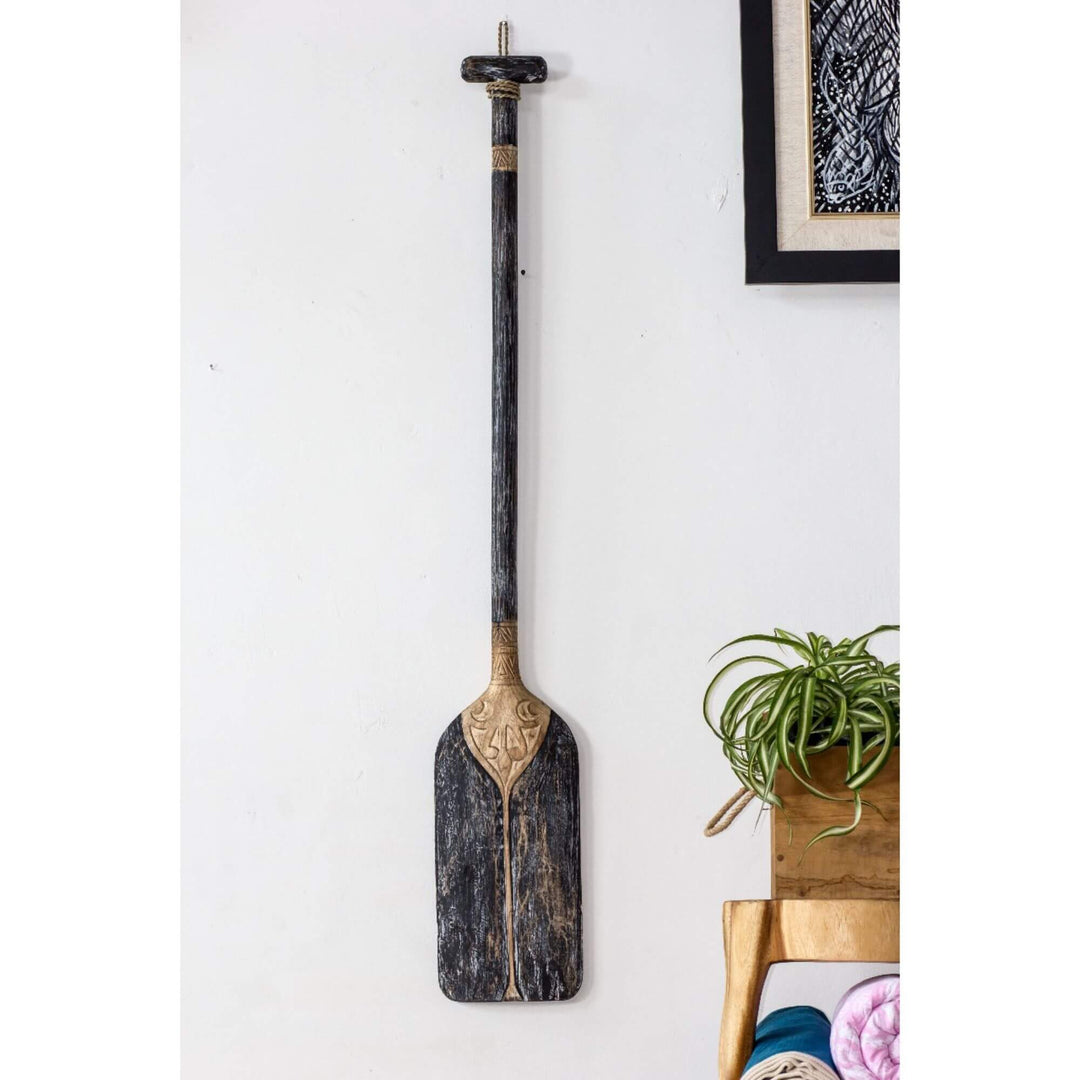 Black paddle wall decor with carved details on display.
