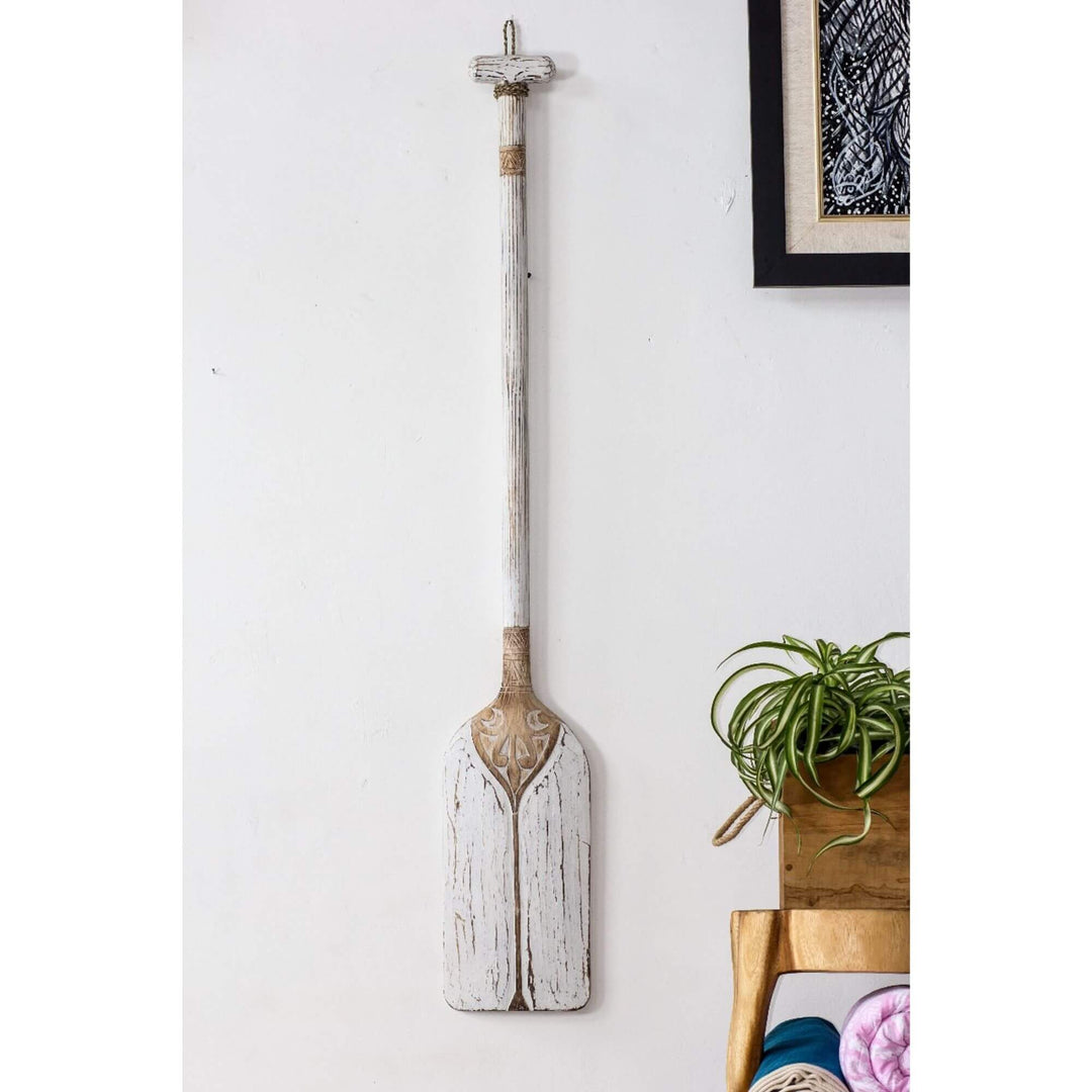 White paddle wall decor with rustic texture and carved top.