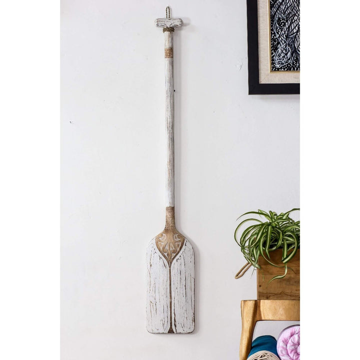White paddle wall decor with rustic texture and carved top.