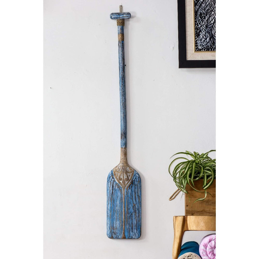 Blue paddle wall decor with distressed paint and detailed carvings.

