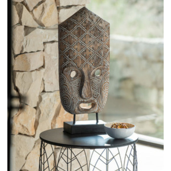 Styled interior view of Tribal Mask Stand placed on a console, highlighting its graphic carved details.