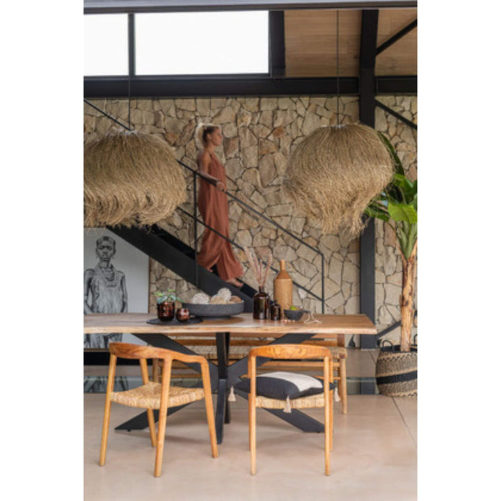 Styled interior with Tribe Boy Canvas leaning against a stone wall behind a dining table.

