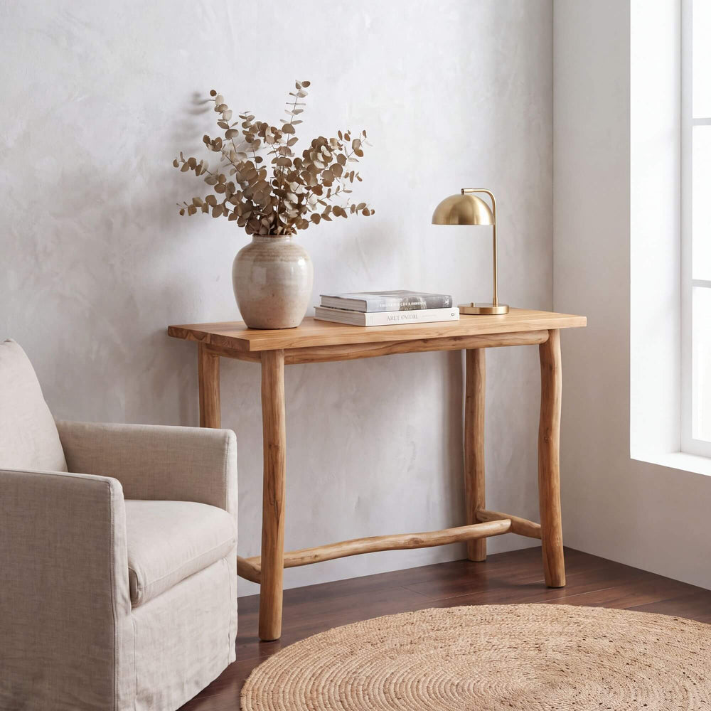 Tupai teak wood console table styled with books, a lamp, and a decorative vase in a bright living room