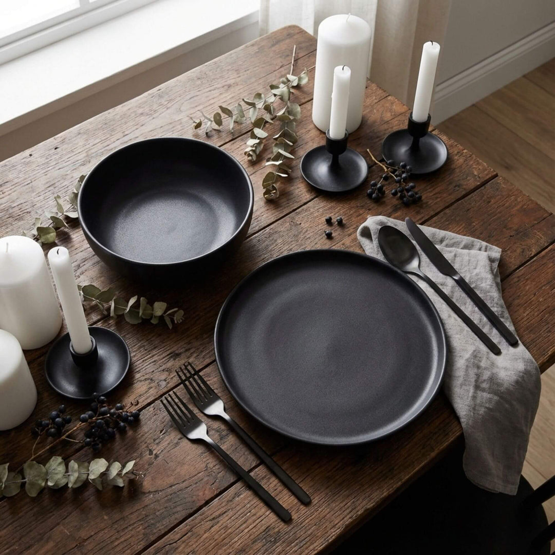 Uno Black tableware styled on a dining table with candles and dark accessories.