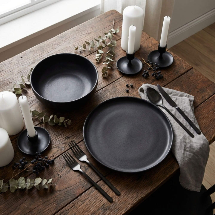 Uno Black tableware styled on a dining table with candles and dark accessories.