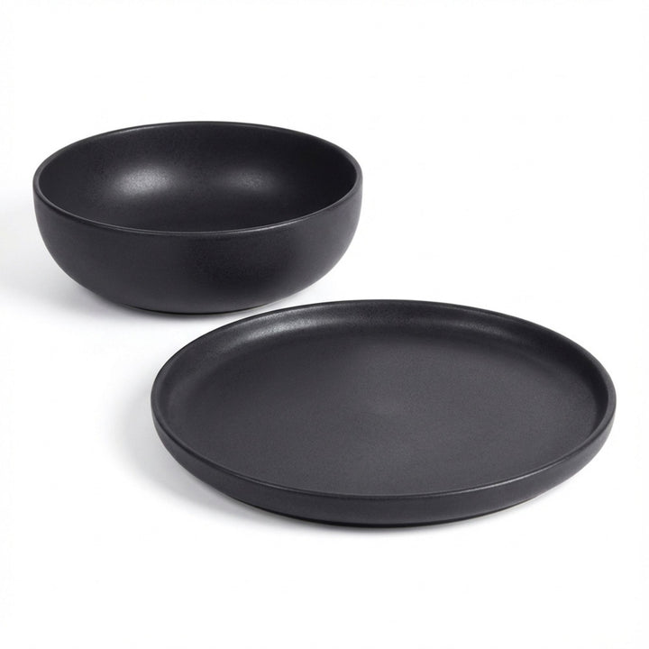 Set of Uno Black ceramic tableware including plate and bowl on a white background.