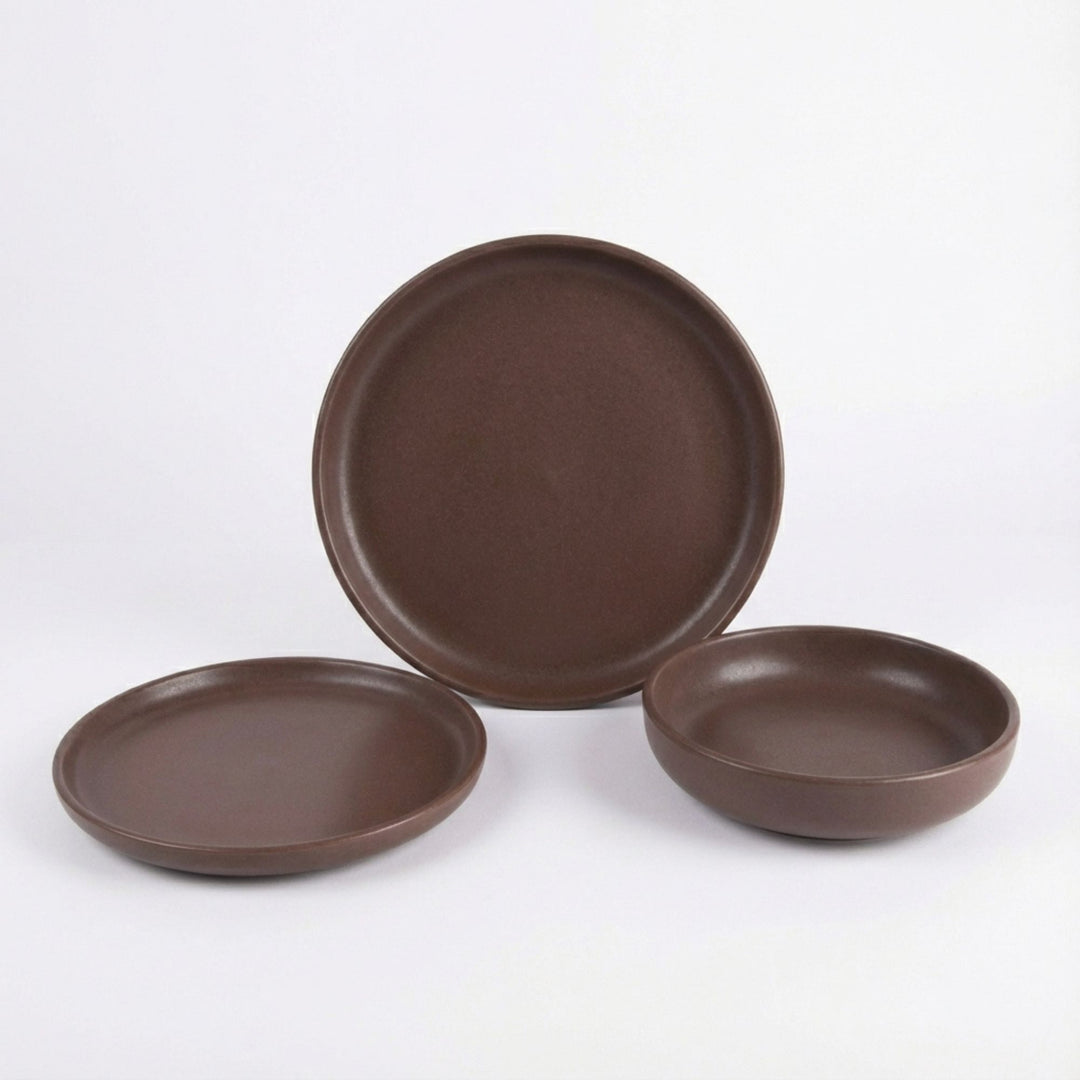 Set of Uno Choco ceramic tableware in chocolate brown displayed on a white background.