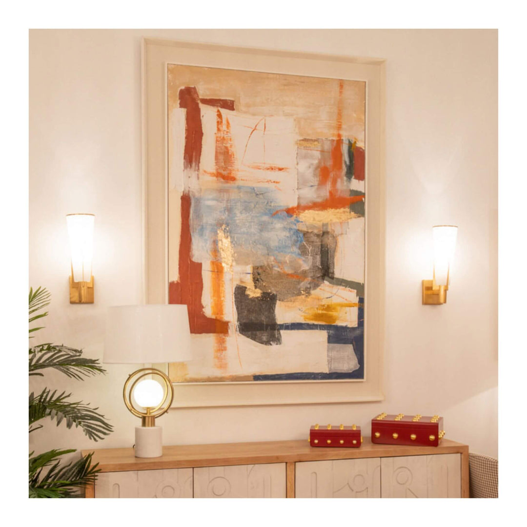 Urban Spirit Painting hanging on a neutral wall between two gold wall lamps, above a wooden sideboard with modern decor — abstract art in blue, rust, and gold tones.