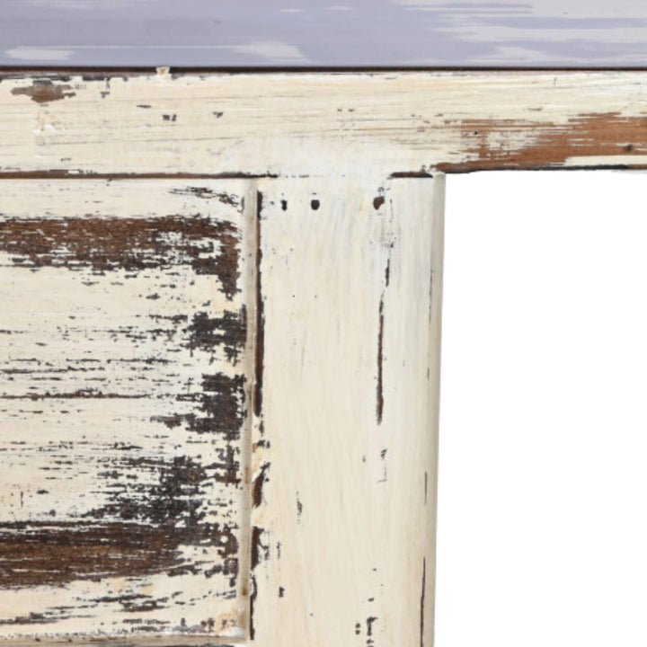 Close-up of the table edge and leg showing the aged white finish and worn wood texture.