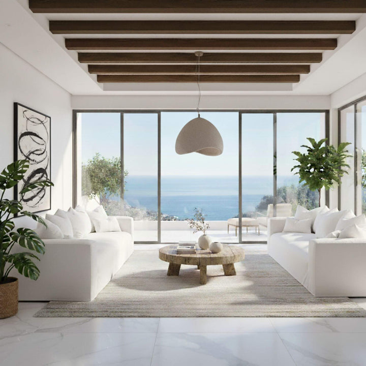 Modern living room with two Verona sofas, a wooden coffee table, and large windows overlooking a scenic view.