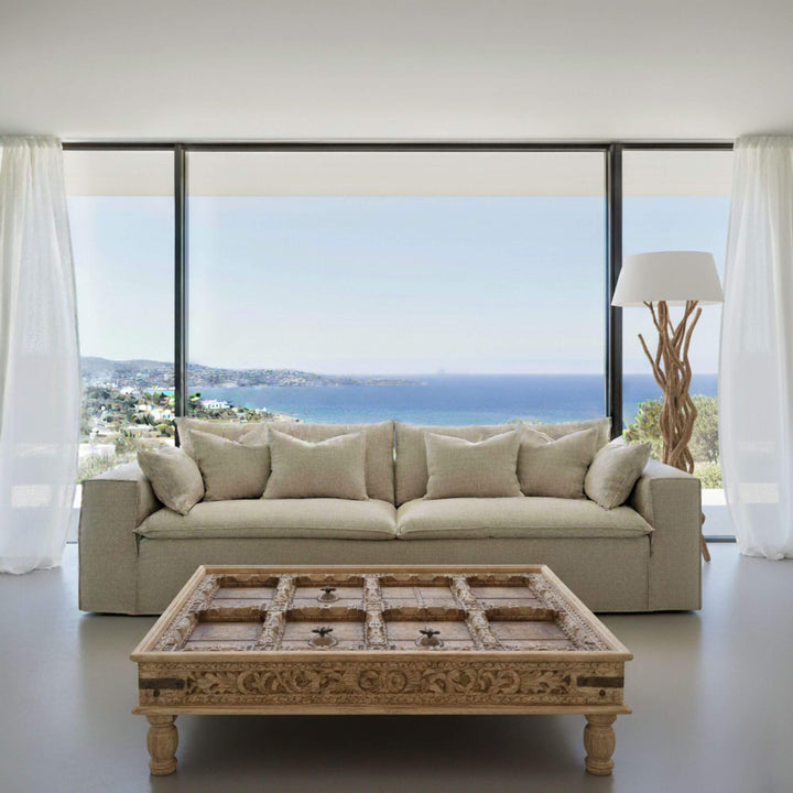 Beige Vivenza sofa with a decorative coffee table in a room with large windows overlooking a scenic view.