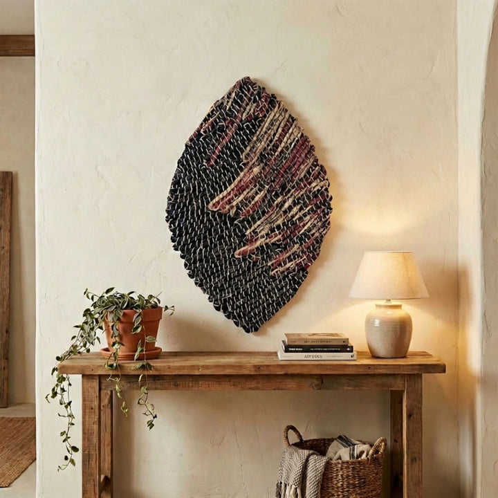 Woven Warna wall deco art piece on a neutral wall above a wooden console table with decor items.