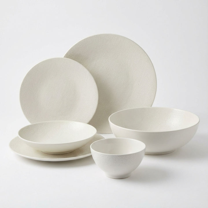 White Vesuvio ceramic tableware set with plates and bowls in a minimalist design.
