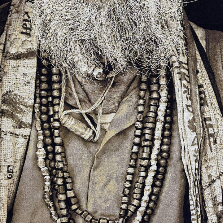 Close-up of the Wise Baba Man tapestry highlighting layered necklaces and textured fabric details.