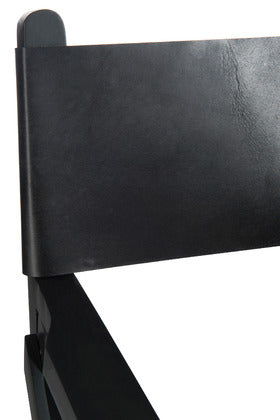 Close-up of black leather backrest and teak wood detail.