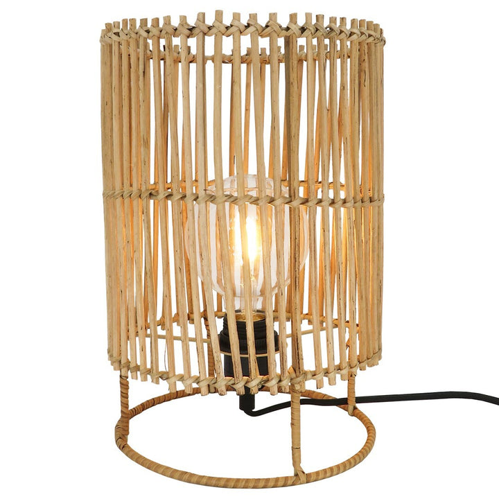 Small Sun Rattan Lamp standing on table with warm glow.