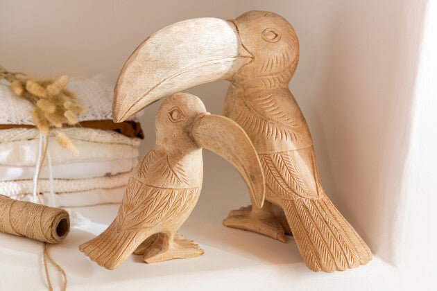Tucan figures styled together in an interior setting with organic decor.